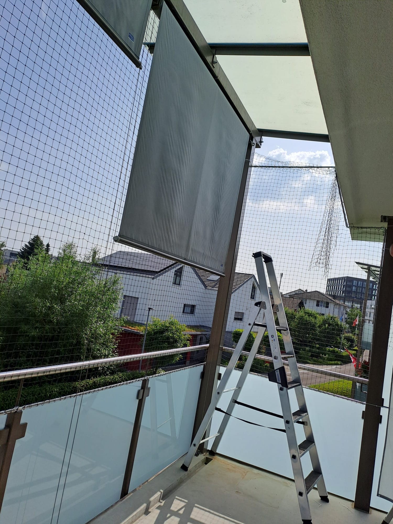 Katzenschutznetz auf einem Balkon als Fallschutz für die Katzen. Schützt die Haustiere vor dem Herunterfallen und entlaufen. Bei der Arbeit mit Leiter. Sonderhöhe von 3.5Meter