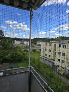 Katzennetzmontage auf einem Balkon, als Absturzsicherung für die Katzen. Schützt die Haustiere vor dem Herunterfallen und entlaufen. Aussicht aus dem 6.OG. Aussparung für die Handkurbel der Sonnenmarkise. Hochwertige Materialien